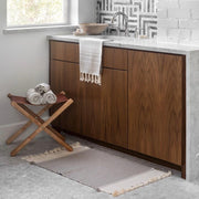 Woven bath mat in front of modern vanity, stone-grey