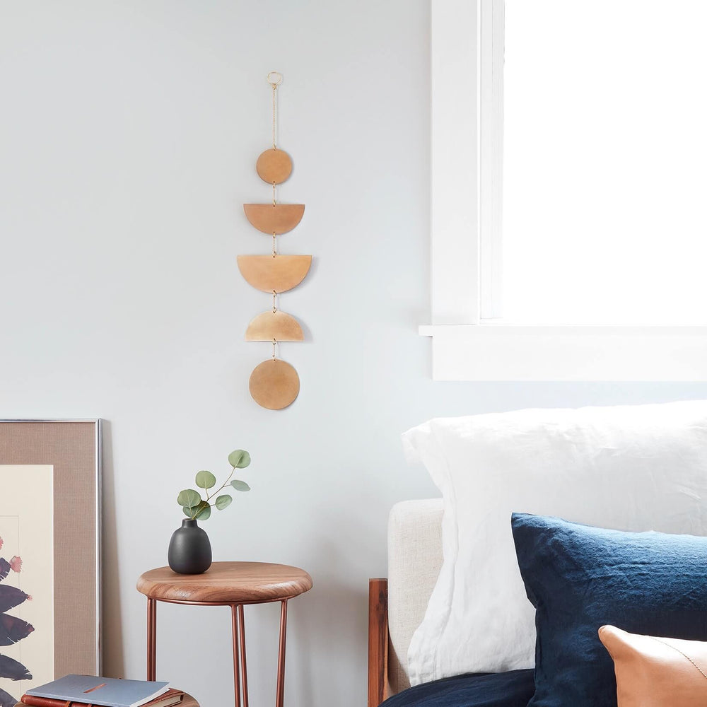 Geometric brass wall hanging next to bed