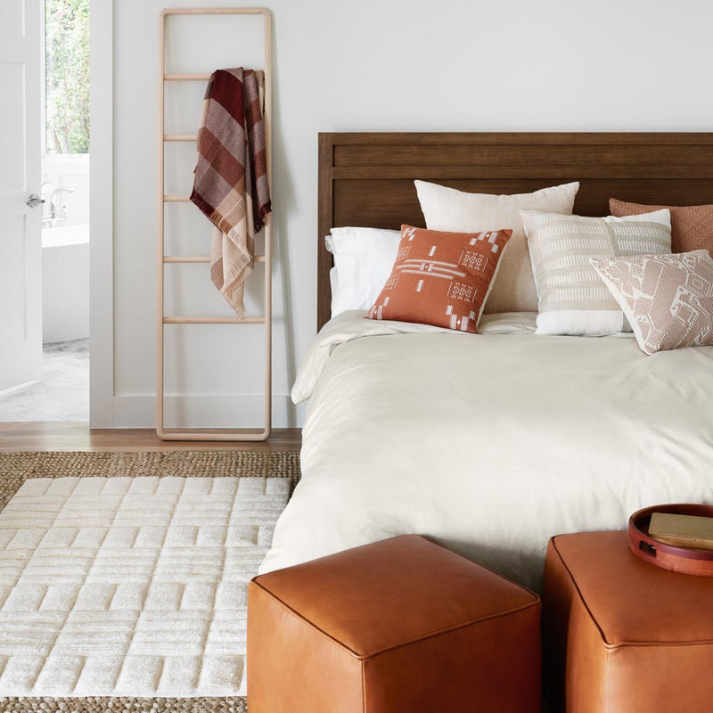 Leather ottomans in front of bed with throw pillows, solid-sand