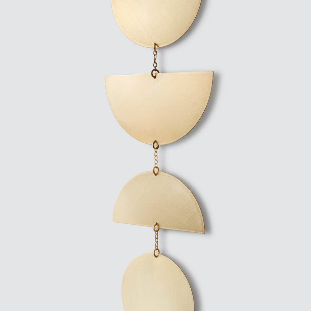 Detailed view of chain links between each brass piece of metal wall hanging