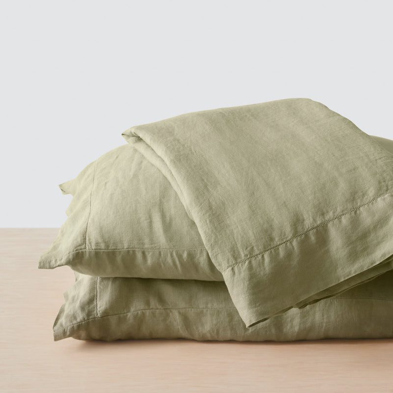 Top sheet folded on stack of two sage green pillows, sage