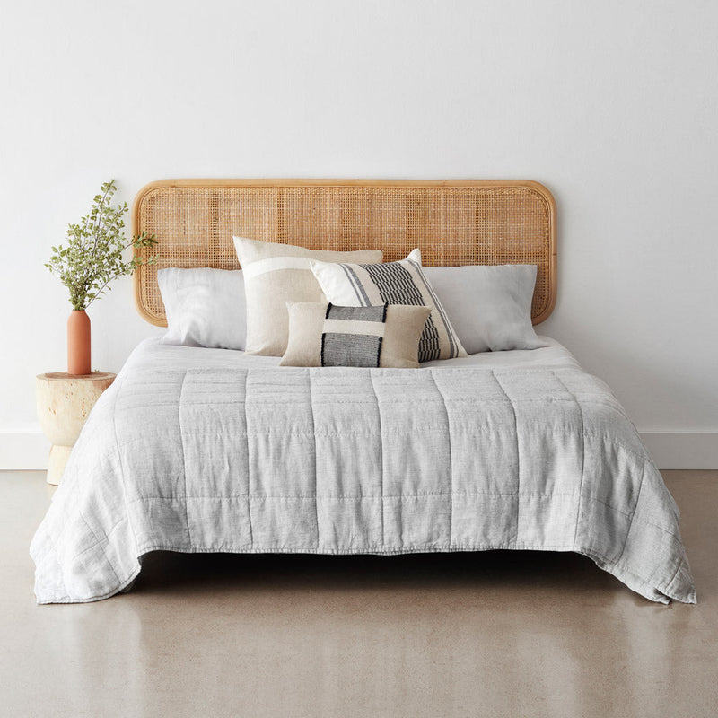 Graphite stripe linen quilt on styled bed with rattan headboard, graphite-stripe