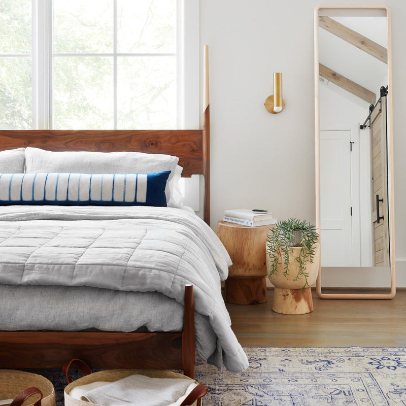 Styled bedroom with indigo dyed lumbar and light grey linen quit folded at end of bed, light-grey