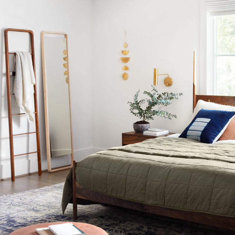 Styled bedroom with olive green linen quilt and multiple pillows, olive