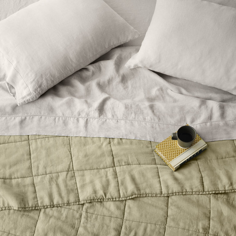 Overhead of sage green linen quilt and sand sheet set, sage