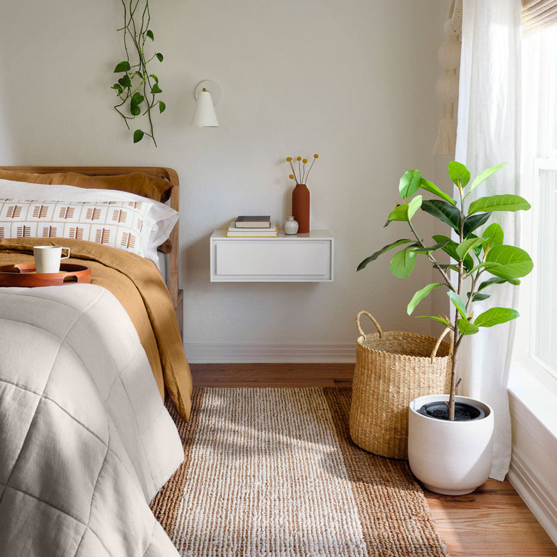 Sand linen quilt folded at foot of styled bed, solid-sand