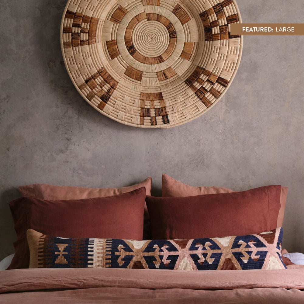 Zomba woven wall hanging over bed with rose linen bedding