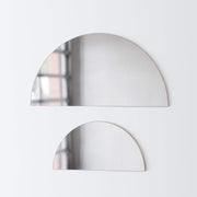 Large half moon mirror hanging over small half moon mirror, smoke